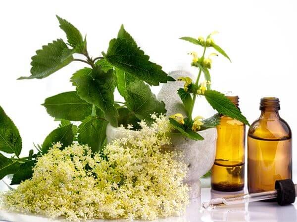 Boccette di oli vegetali con dei fiori accanto